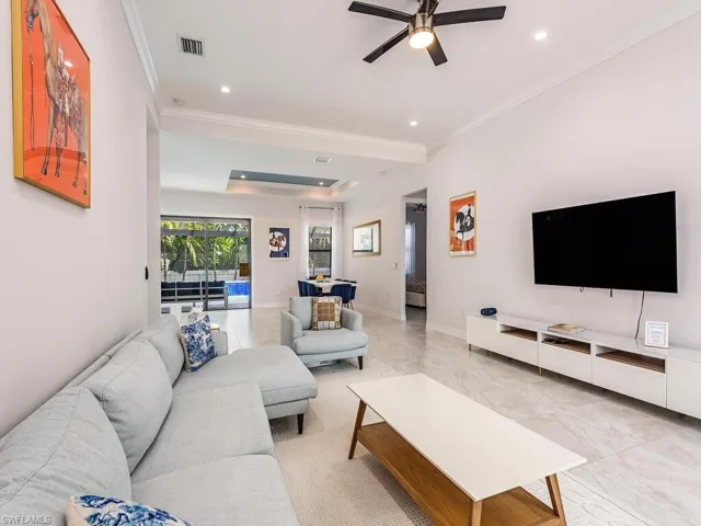 Living area with ornamental molding, ceiling fan, light tile patterned flooring, a raised ceiling, and recessed lighting