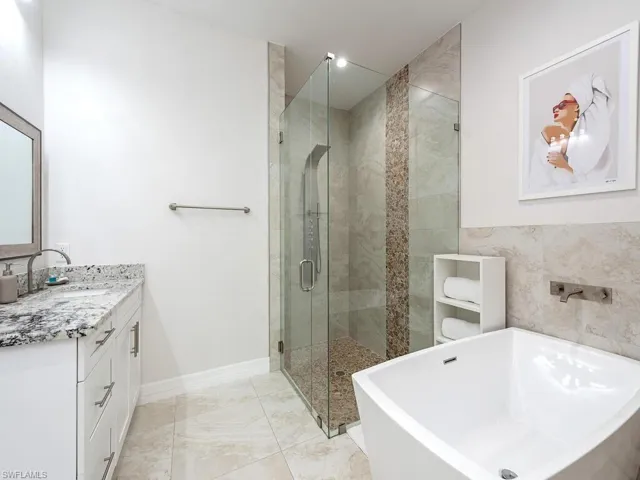Full bath featuring vanity, a soaking tub, and a stall shower