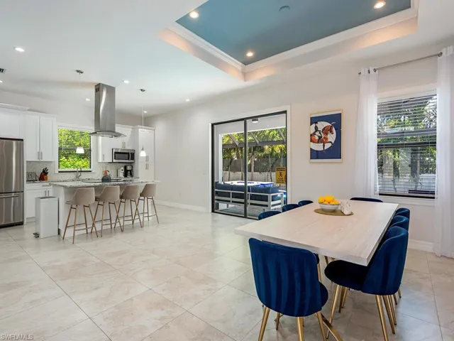 Dining room with a tray ceiling, healthy amount of natural light, recessed lighting, crown molding, and light tile patterned floors