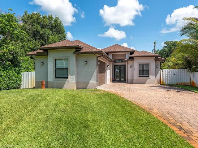 View of front of property featuring an attached garage, stucco siding, decorative driveway, and roof with shingles