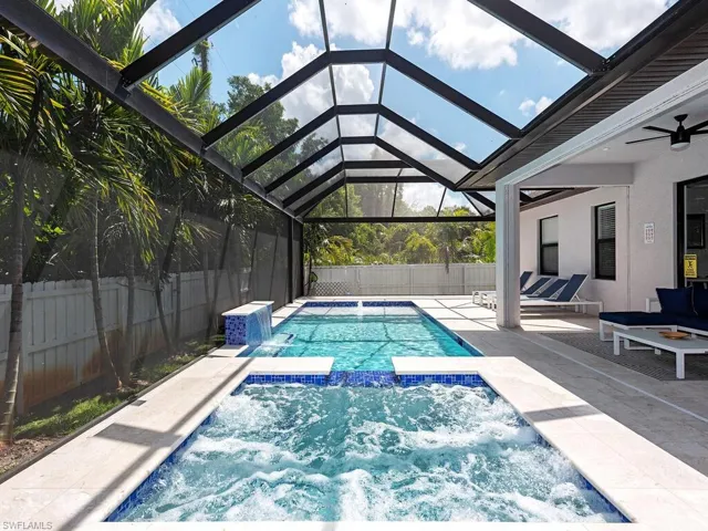 View of swimming pool with glass enclosure, a patio, a pool with connected hot tub, ceiling fan, and a sunroom
