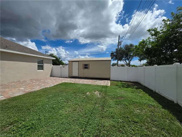 Expansive backyard featuring a privacy fence, a paved patio area, and a detached storage shed