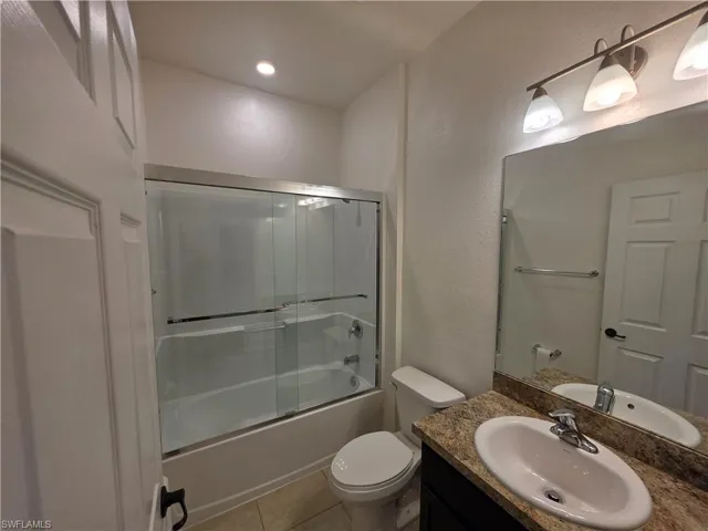 Bathroom featuring a vanity with a stone-finish countertop, undermount sink, and wall-mounted mirror