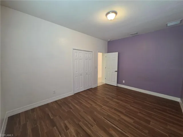 Wood-finish flooring, white bi-fold closet doors, and neutral wall paint