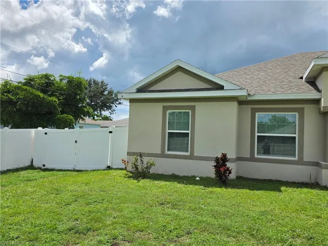 Exterior stucco finish with white vinyl fencing and a shingle roof