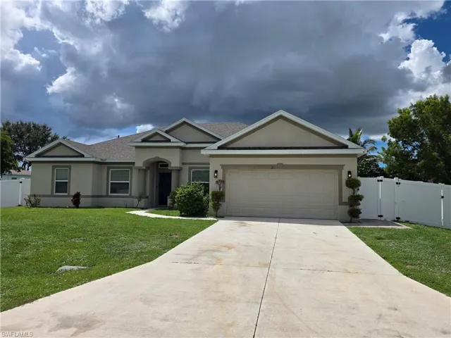 Stucco exterior with multiple gables, an attached two-car garage, a concrete driveway, and a white privacy fence