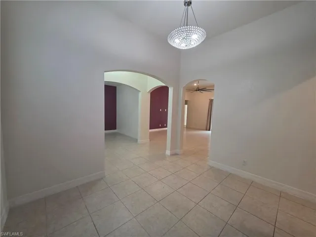 Recessed archways, tile flooring, and a decorative chandelier