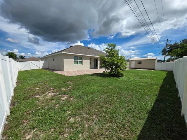 Fenced backyard featuring a paver patio, stucco exterior, and a detached storage shed