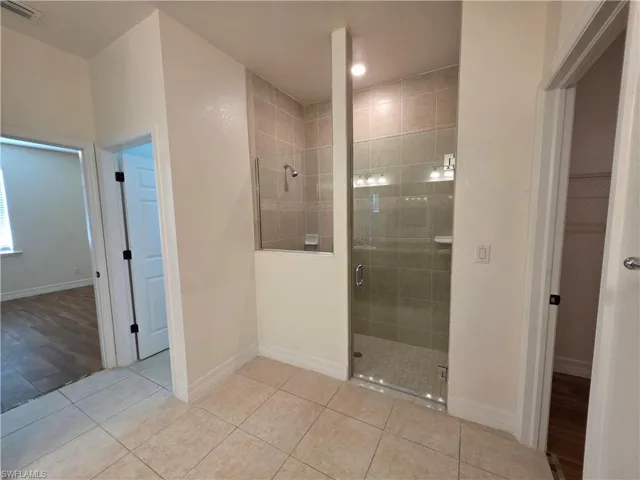 Tiled flooring complemented by a walk-in shower with glass enclosure and full-height tiling