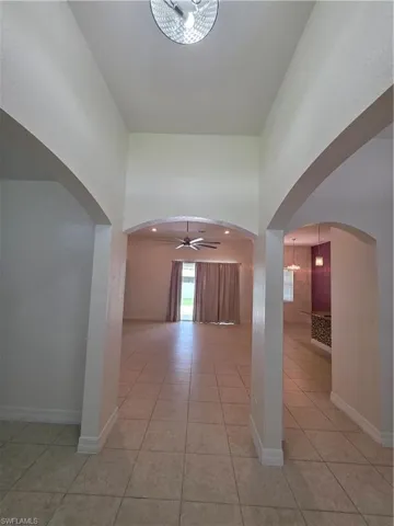 Vaulted ceilings with recessed lighting, arched doorways, tile flooring, and a ceiling fan