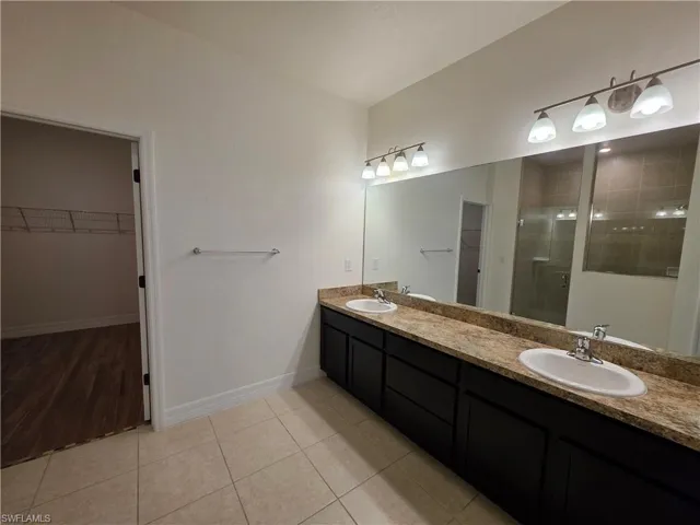 Double vanity with undermount sinks, stone-look countertop, and dark wood-finish cabinetry