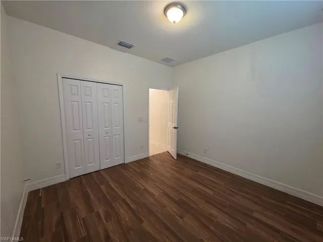 Wood-finish flooring, white bifold closet doors, and a flush mount ceiling light fixture