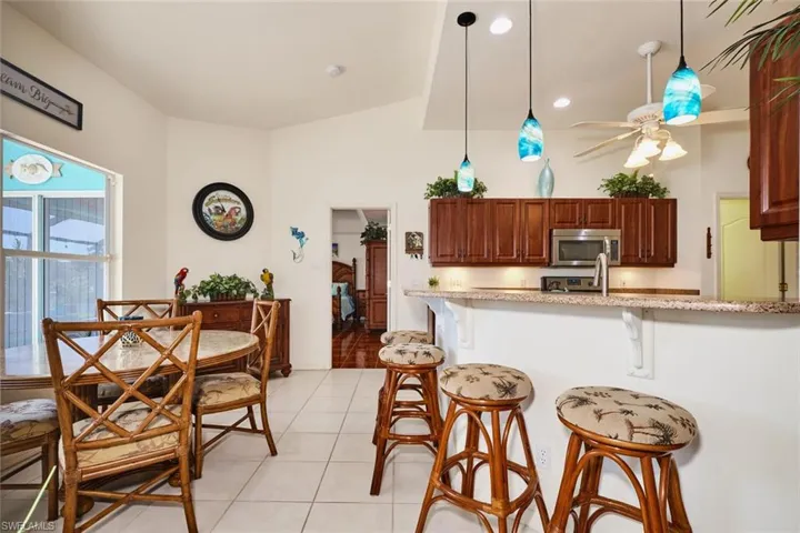 Kitchen featuring pendant lighting, light tile patterned floors, a ceiling fan, a breakfast bar