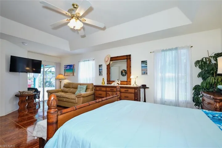 Bedroom featuring a tray ceiling, access to exterior, and ceiling fan