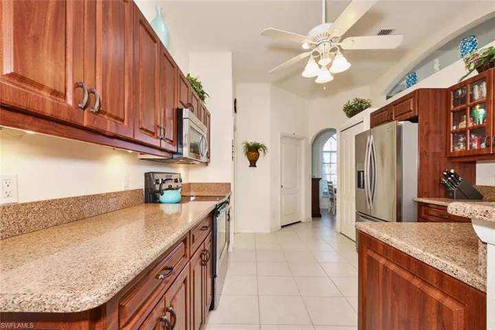 Kitchen with Stylestone counters and glass insert cabinets, light tile