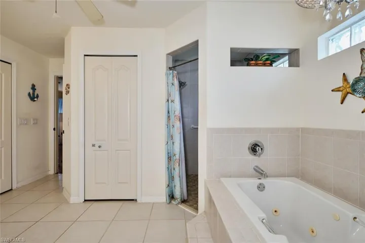 Featuring a tile shower, tile patterned floors, baseboards, and a whirlpool tub