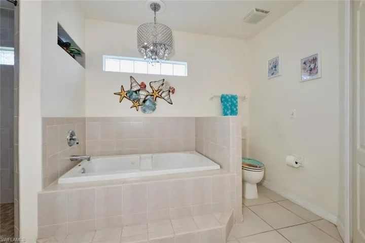 Full bathroom with a wealth of natural light and an inviting chandelier