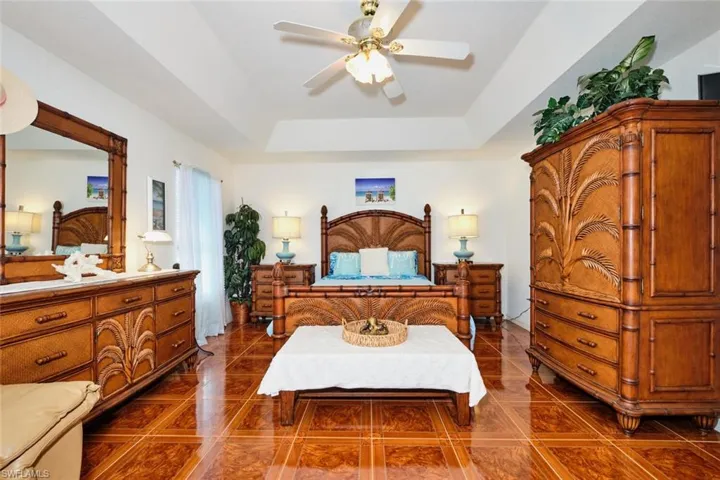 Bedroom with tile patterned flooring, a raised ceiling, and a ceiling fan