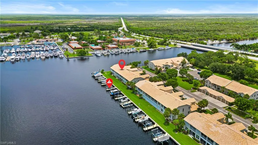 Waterfront development featuring multiple buildings with terracotta-style roofs, private boat docks, and manicured green spaces