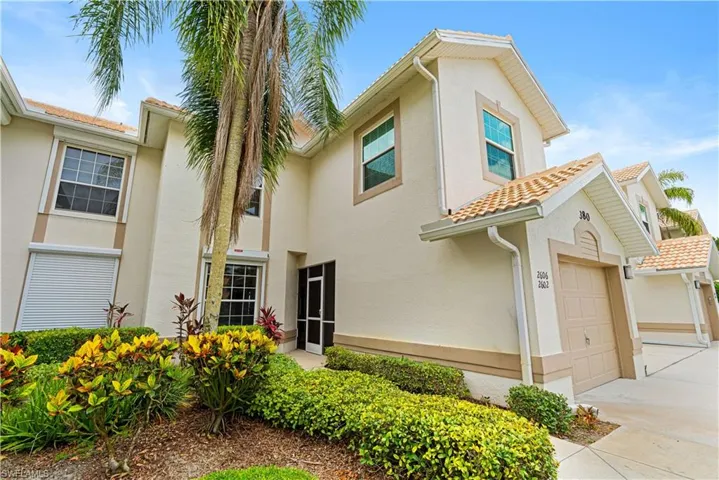 Stucco exterior featuring a tile roof, single-car garage, manicured landscaping, and a screened entry