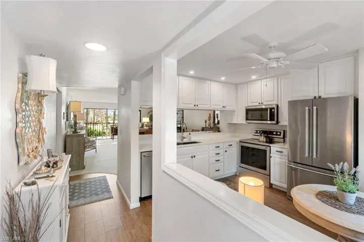 Kitchen featuring light hardwood / wood-style floors, ceiling fan, white cabinetry, and appliances with stainless steel finishes