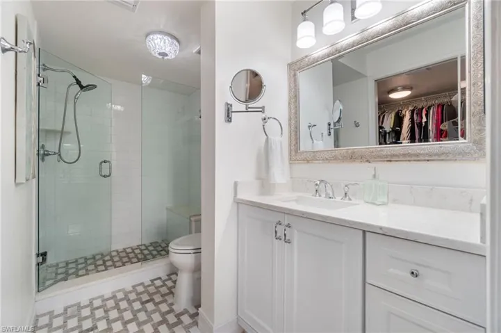 Bathroom featuring toilet, vanity, tile patterned flooring, and a shower with door