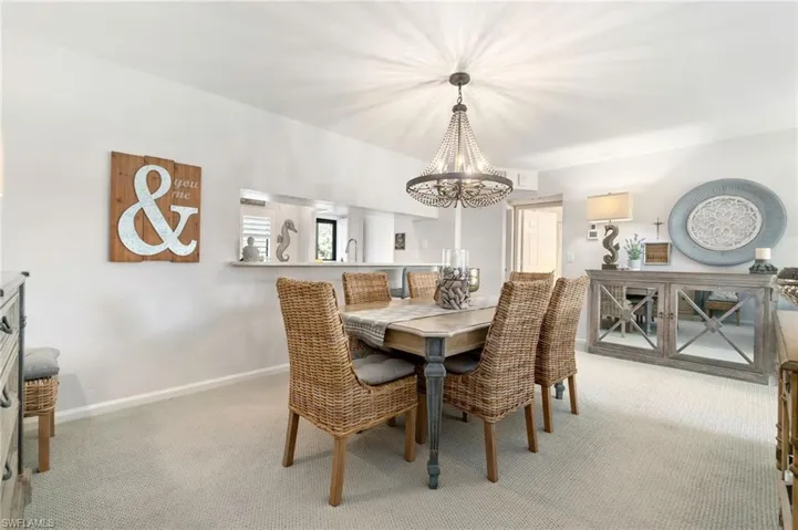 Dining space featuring light colored carpet and a notable chandelier