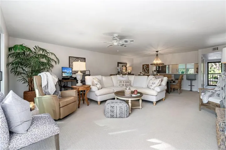 Carpeted living room with ceiling fan with notable chandelier