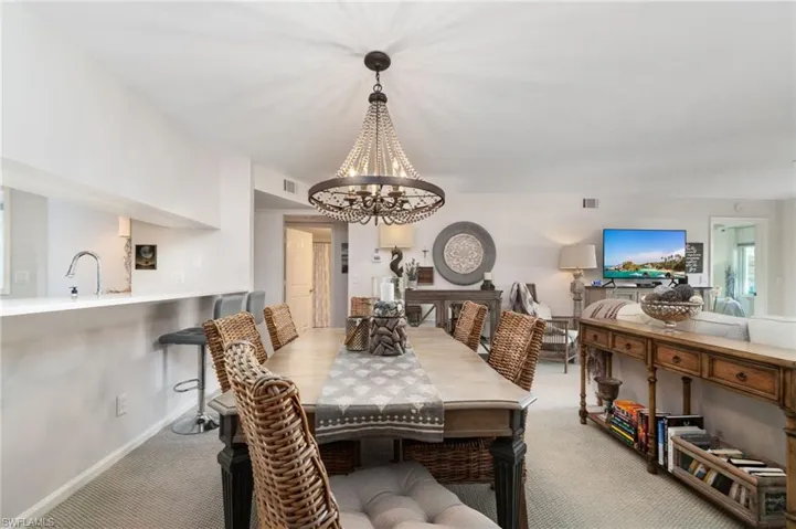 Dining area with light carpet, sink, and a notable chandelier
