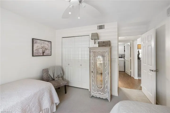 Bedroom featuring washer / clothes dryer, light hardwood / wood-style floors, ceiling fan, and a closet