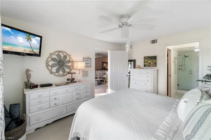 Bedroom with carpet floors, ceiling fan, and ensuite bath