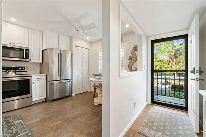Kitchen with white cabinetry, light wood-type flooring, appliances with stainless steel finishes, and ceiling fan