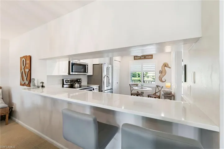 Kitchen with kitchen peninsula, appliances with stainless steel finishes, carpet, and white cabinets