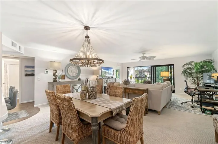 Dining area featuring light carpet and ceiling fan with notable chandelier