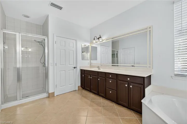 Full bathroom with light tile patterned flooring, vanity, a bath, and a shower stall