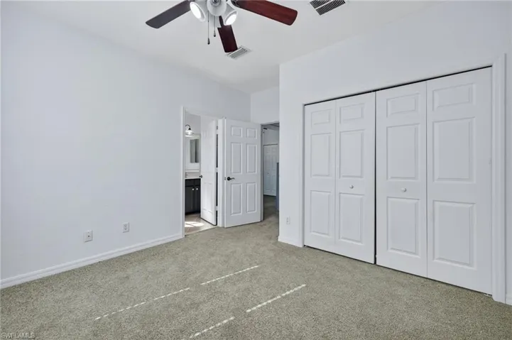 Unfurnished bedroom featuring carpet, a closet, a ceiling fan, and connected bathroom