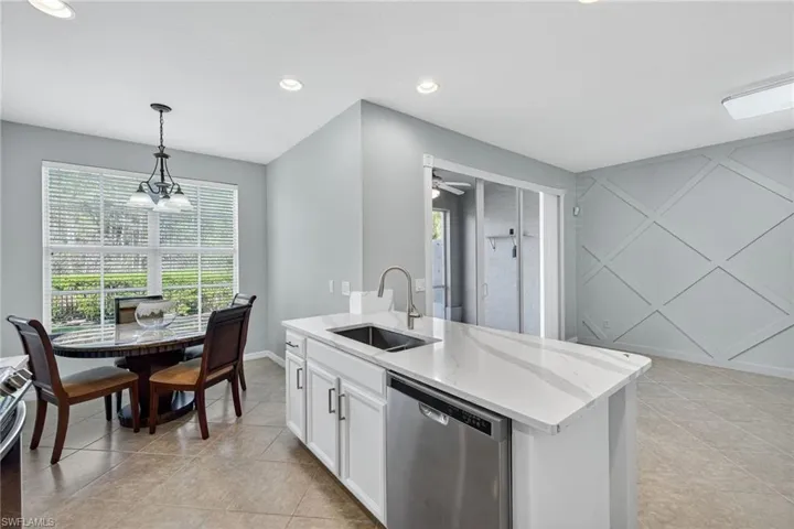 Kitchen featuring stainless steel dishwasher, decorative light fixtures, white cabinets, recessed lighting, and light tile patterned flooring