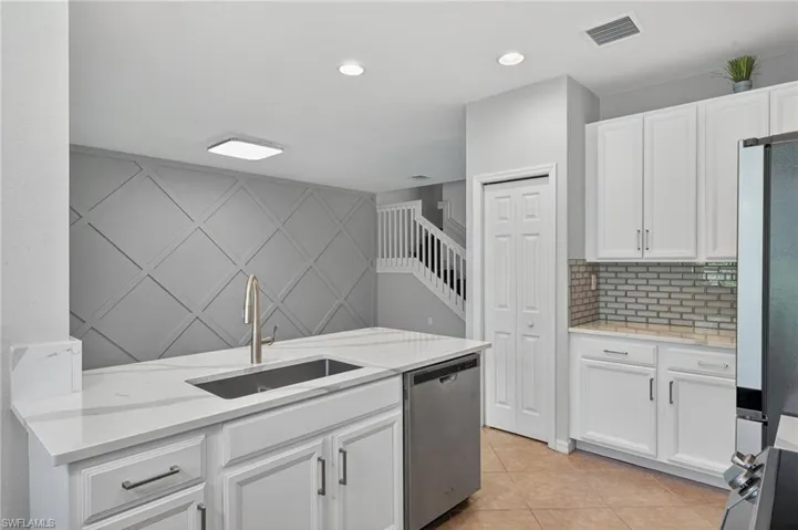Kitchen with appliances with stainless steel finishes, light stone counters, white cabinetry, light tile patterned flooring, and recessed lighting