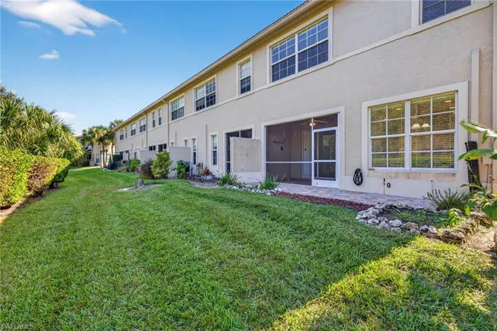 Back of property with stucco siding and a yard