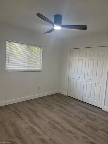 Unfurnished bedroom featuring dark wood-style flooring, ceiling fan, and a closet