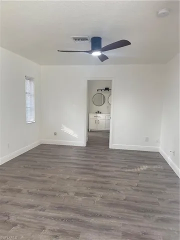 Empty room with dark wood-style flooring, a textured ceiling, a ceiling fan, and a smoke detector