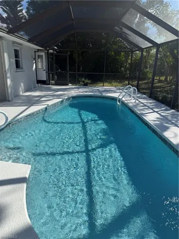 Outdoor pool with a sunroom, glass enclosure, and a patio