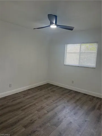 Spare room with dark wood-style floors and baseboards