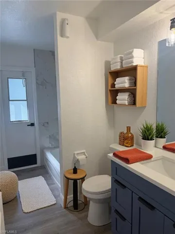 Full bath featuring dark wood-style floors, vanity, a textured wall, and a textured ceiling