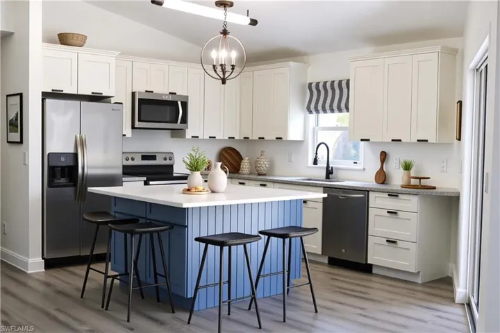 Kitchen featuring appliances with stainless steel finishes, white cabinets, a kitchen breakfast bar, dark wood-style flooring, and lofted ceiling