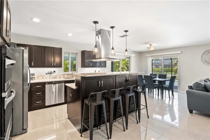 Kitchen featuring decorative light fixtures, a healthy amount of sunlight, stainless steel appliances, and a kitchen island