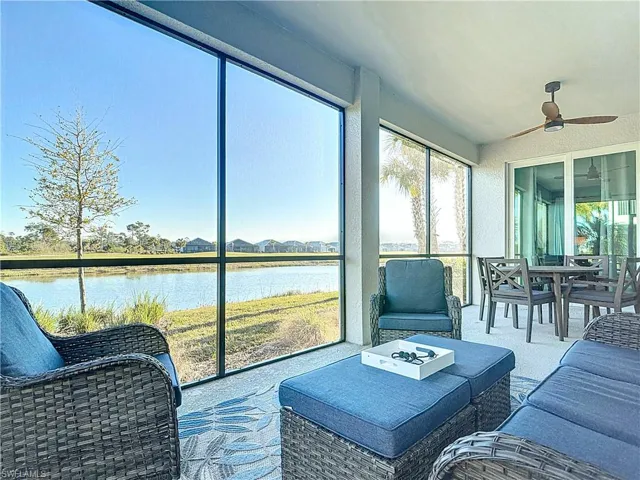 Sunroom / solarium featuring ceiling fan and a water view