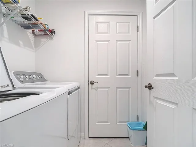 Laundry room with light tile patterned floors and washing machine and clothes dryer