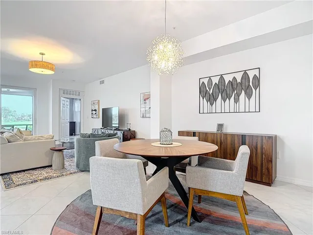 Dining space with light tile patterned flooring and an inviting chandelier