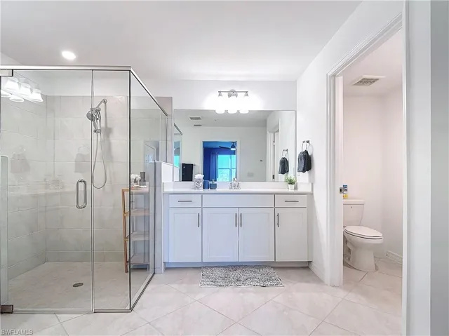 Bathroom with tile patterned flooring, vanity, toilet, and walk in shower